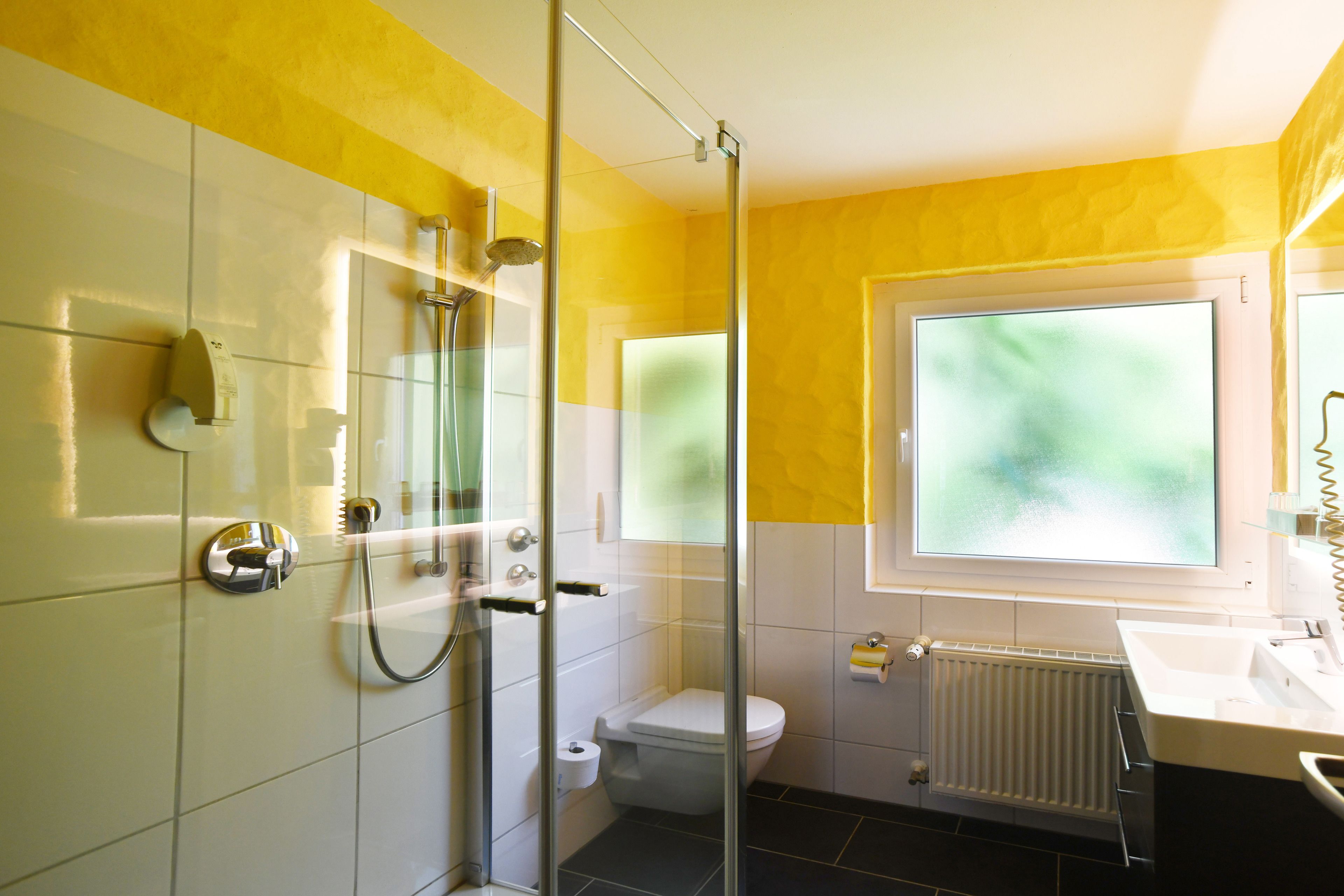 Un baño con ducha de vidrio, inodoro y lavamanos.
