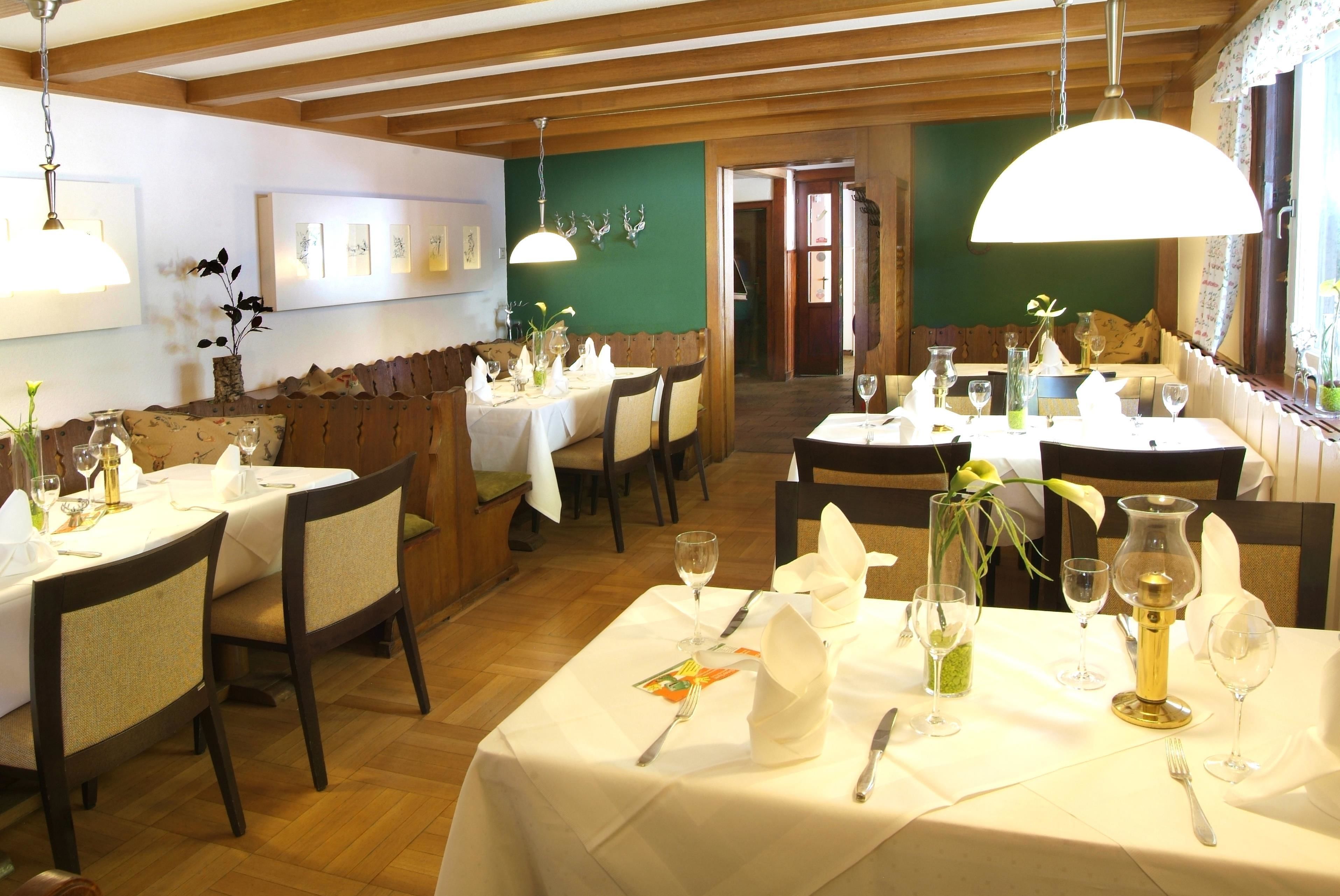 Un restaurante con varias mesas dispuestas para comer, vigas de madera en el techo y obras de arte en las paredes.