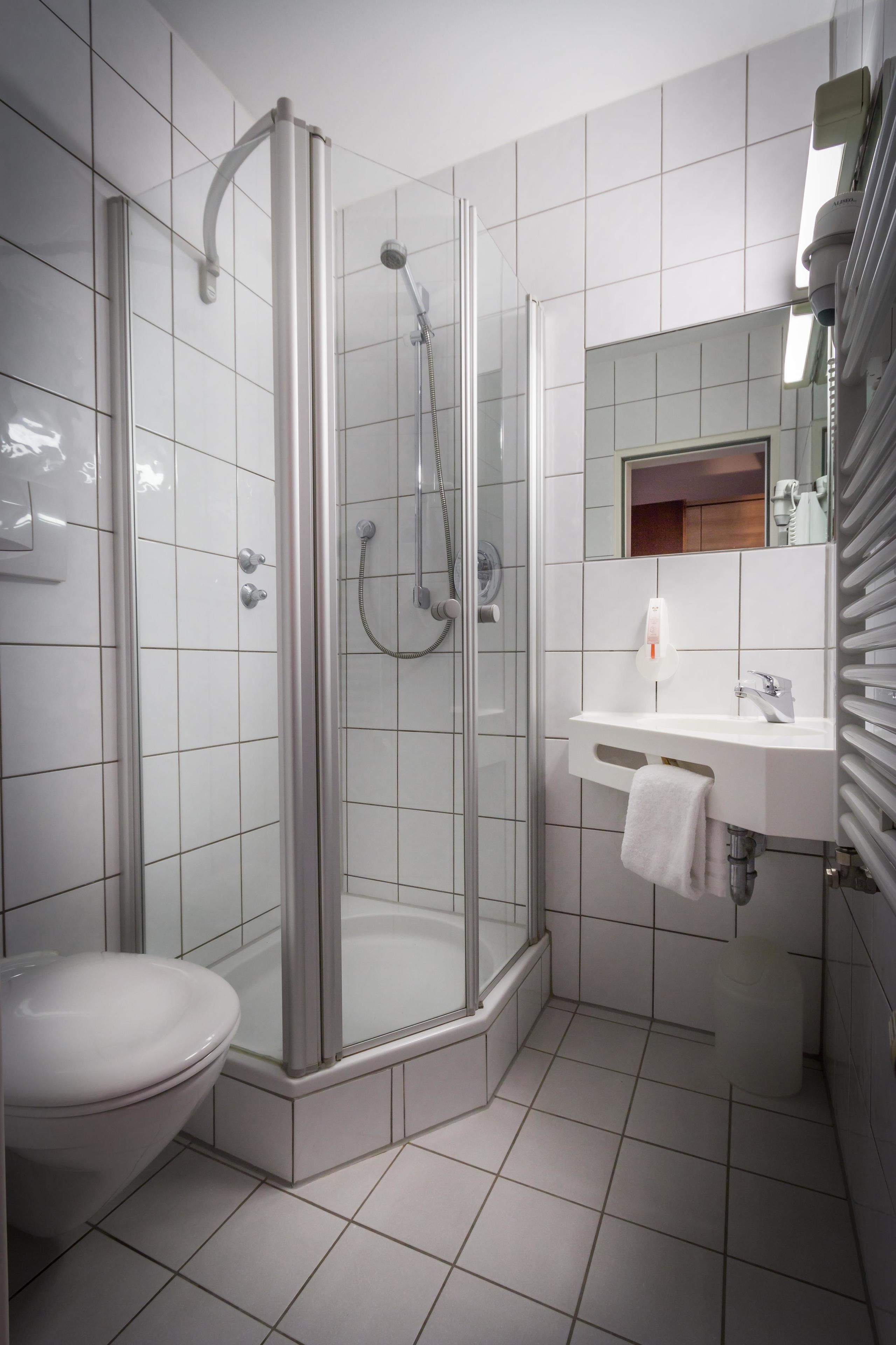 A modern bathroom with a glass-enclosed shower, a white sink, and a toilet.