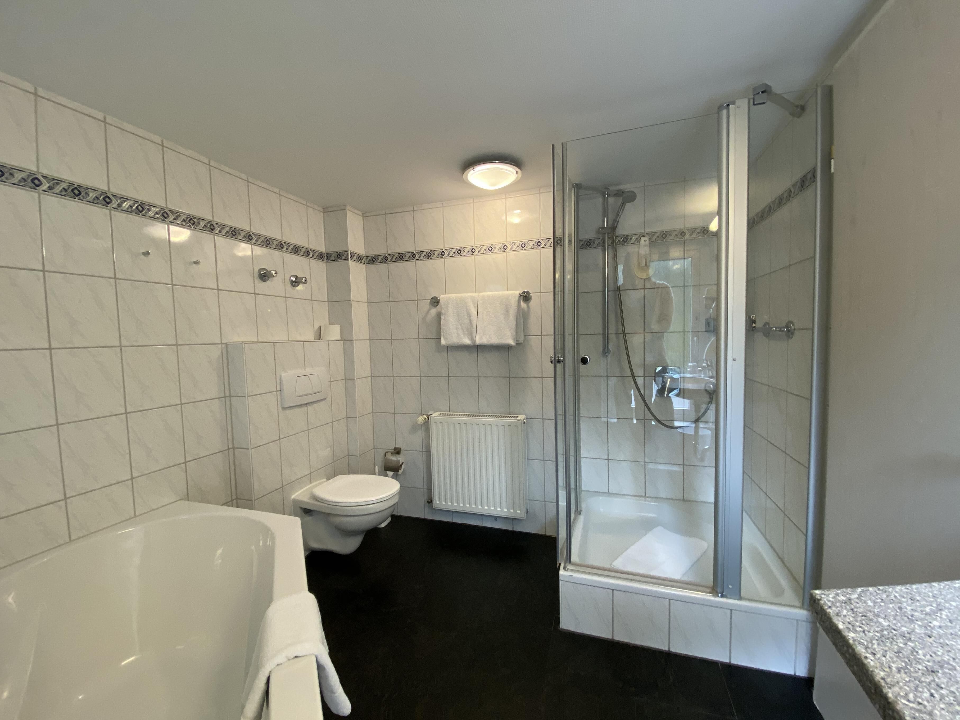 Un baño moderno con bañera, inodoro y ducha con mampara de vidrio.