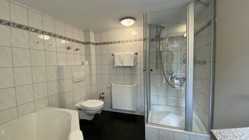 Un baño moderno con bañera, inodoro y ducha con mampara de vidrio.