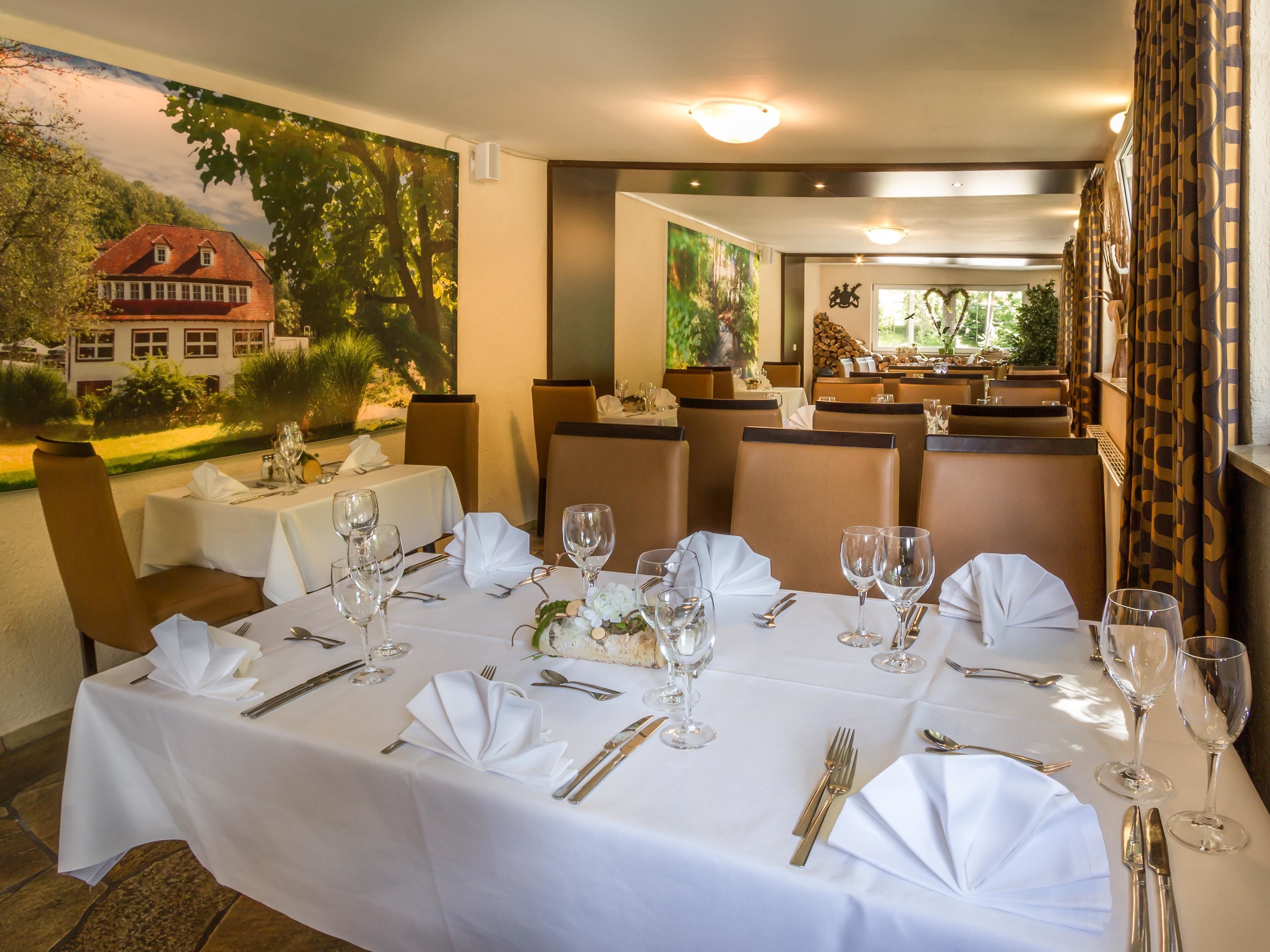 A restaurant with tables set for dining, featuring white tablecloths and gold cutlery.