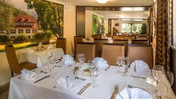 A restaurant with tables set for dining, featuring white tablecloths and gold cutlery.