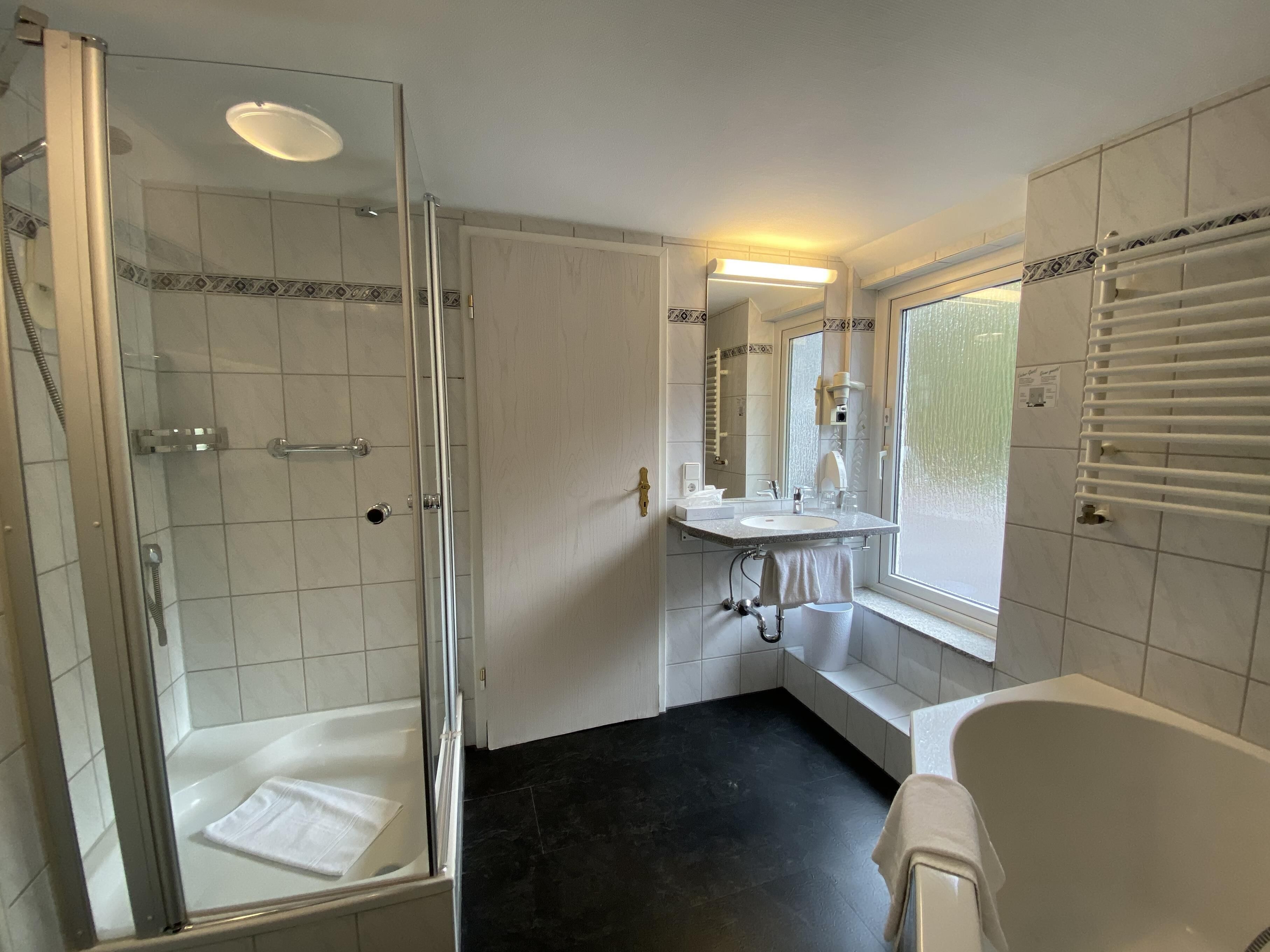 A bathroom with a glass-enclosed shower, a bathtub, and a vanity with a mirror.