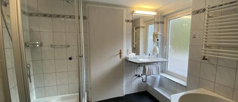 A bathroom with a glass-enclosed shower, a bathtub, and a vanity with a mirror.