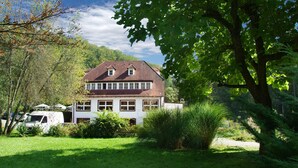 A two-story house with a sloped roof, surrounded by a well-maintained garden and trees. - Hotel Kulinarium an der Glems (Stuttgart)