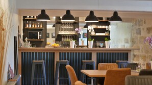 A modern bar area with stools, a counter with bottles, and pendant lighting.
