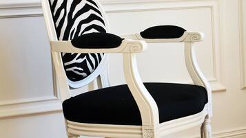 A white upholstered chair with a black cushion and a zebra-patterned pillow.
