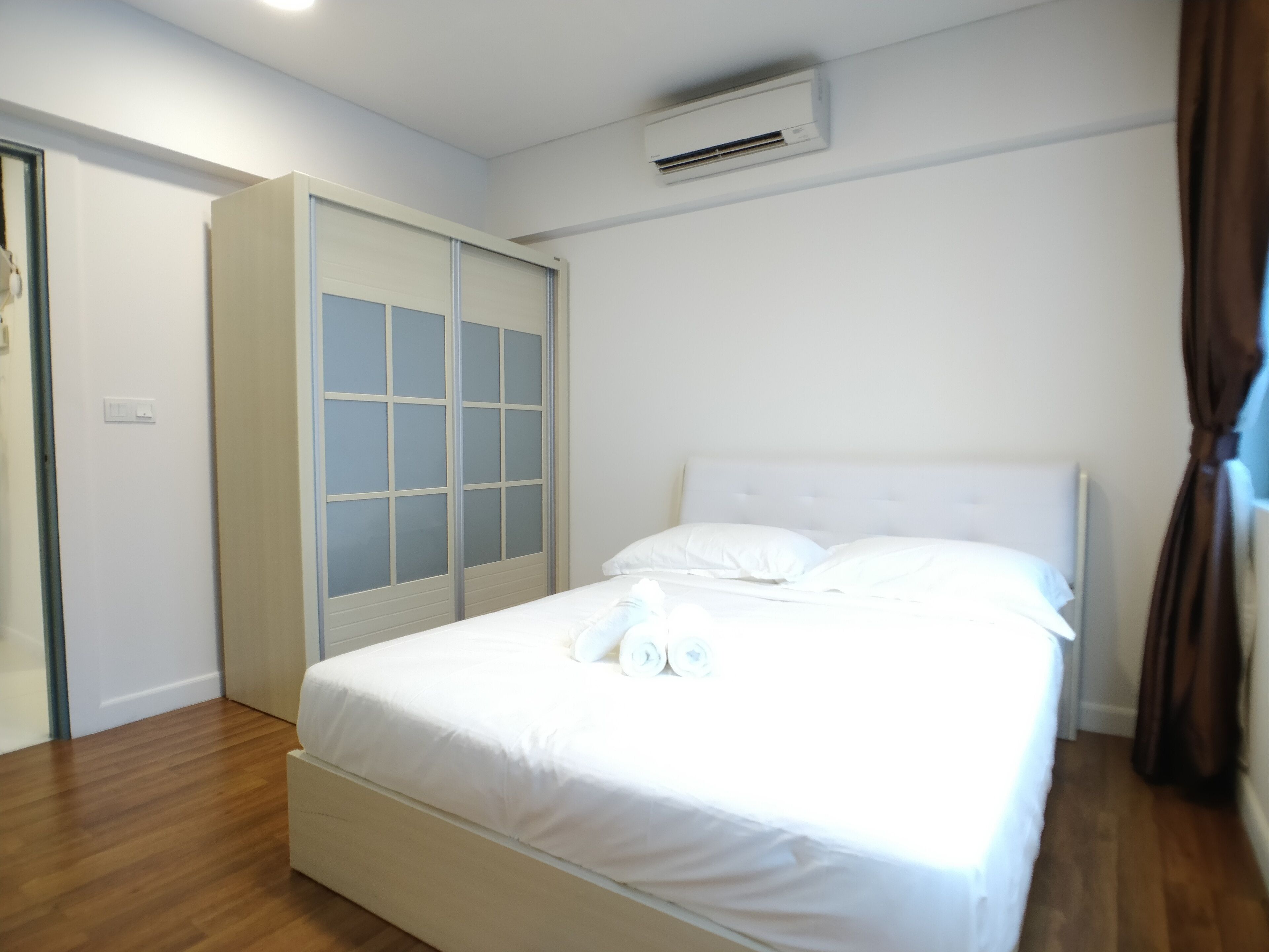 A bedroom with a bed, a wardrobe, and an air conditioning unit.
