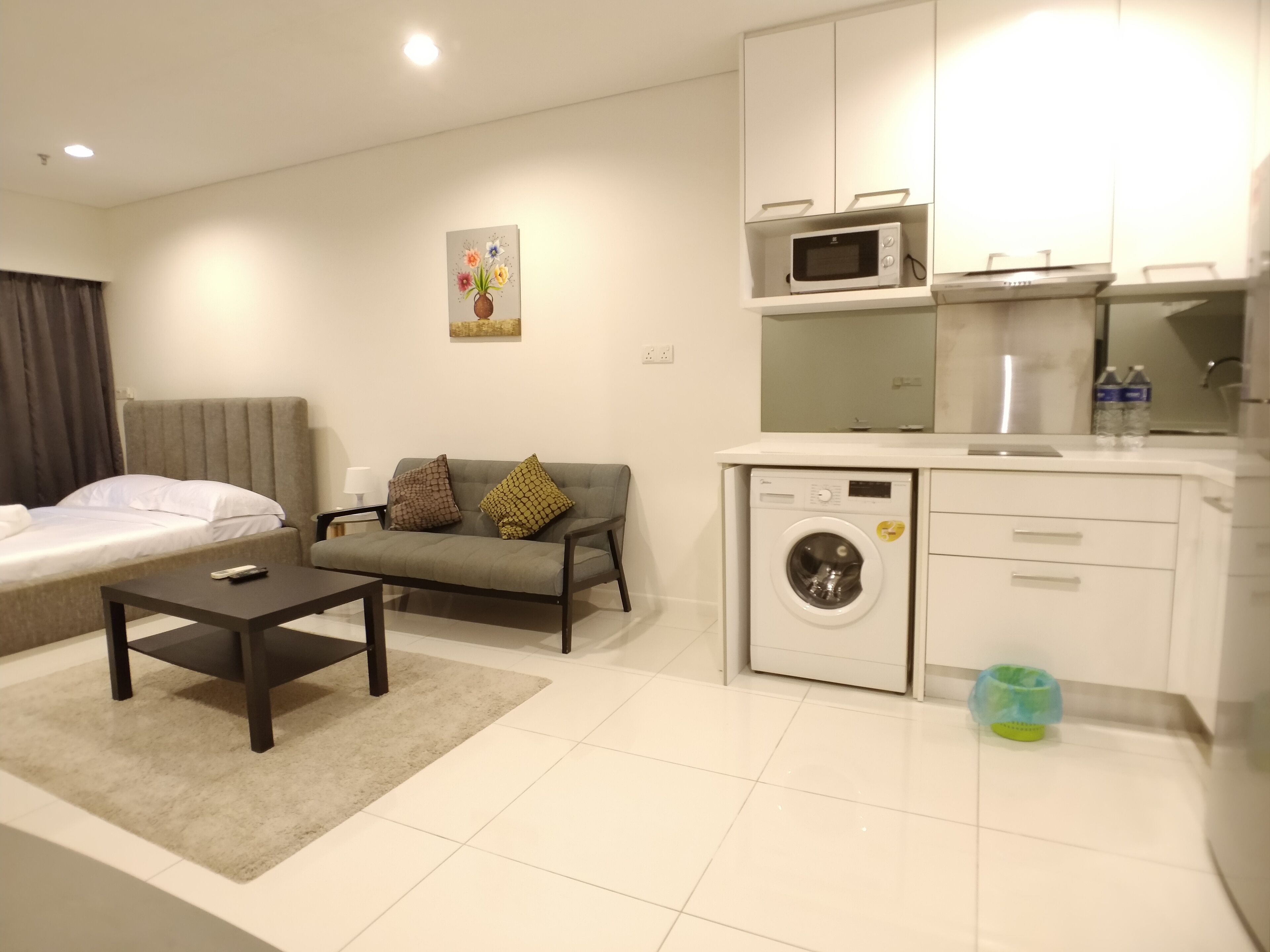 A modern living room with a sofa, a small table, a washing machine, and a microwave.