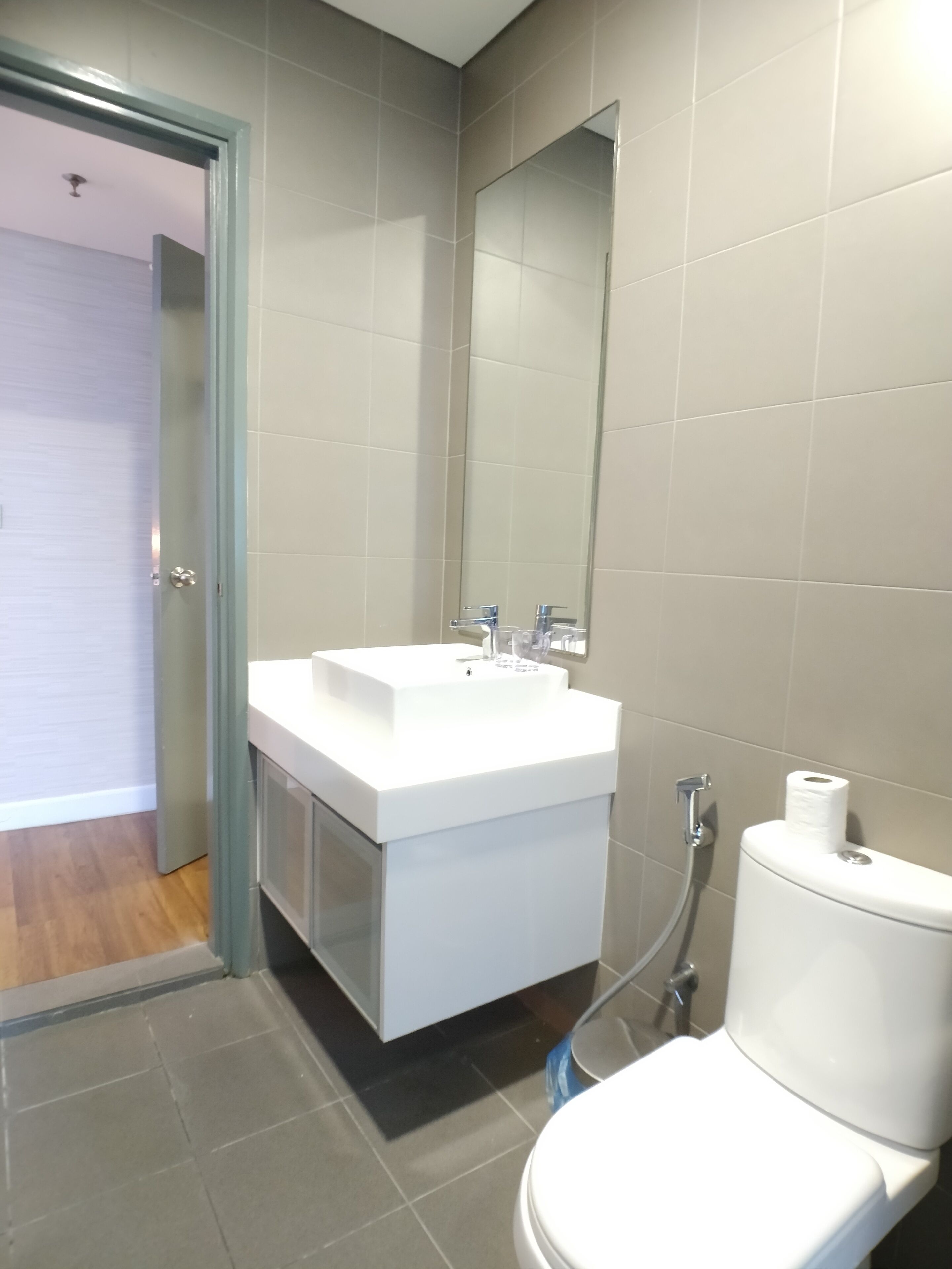 Une salle de bain moderne avec un lavabo, un miroir et des toilettes, le tout de couleur blanche.