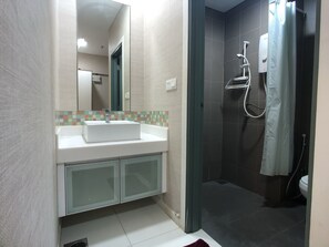 A bathroom with a white sink, a mirror, a shower with a glass door, and tiled walls. - OHO Suites KLCC Summer Suites (Kuala Lumpur)