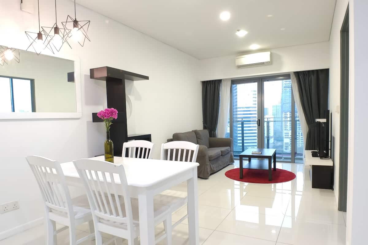Un salon moderne comprenant un coin repas, un canapé, un téléviseur et un balcon offrant une vue sur la ville.