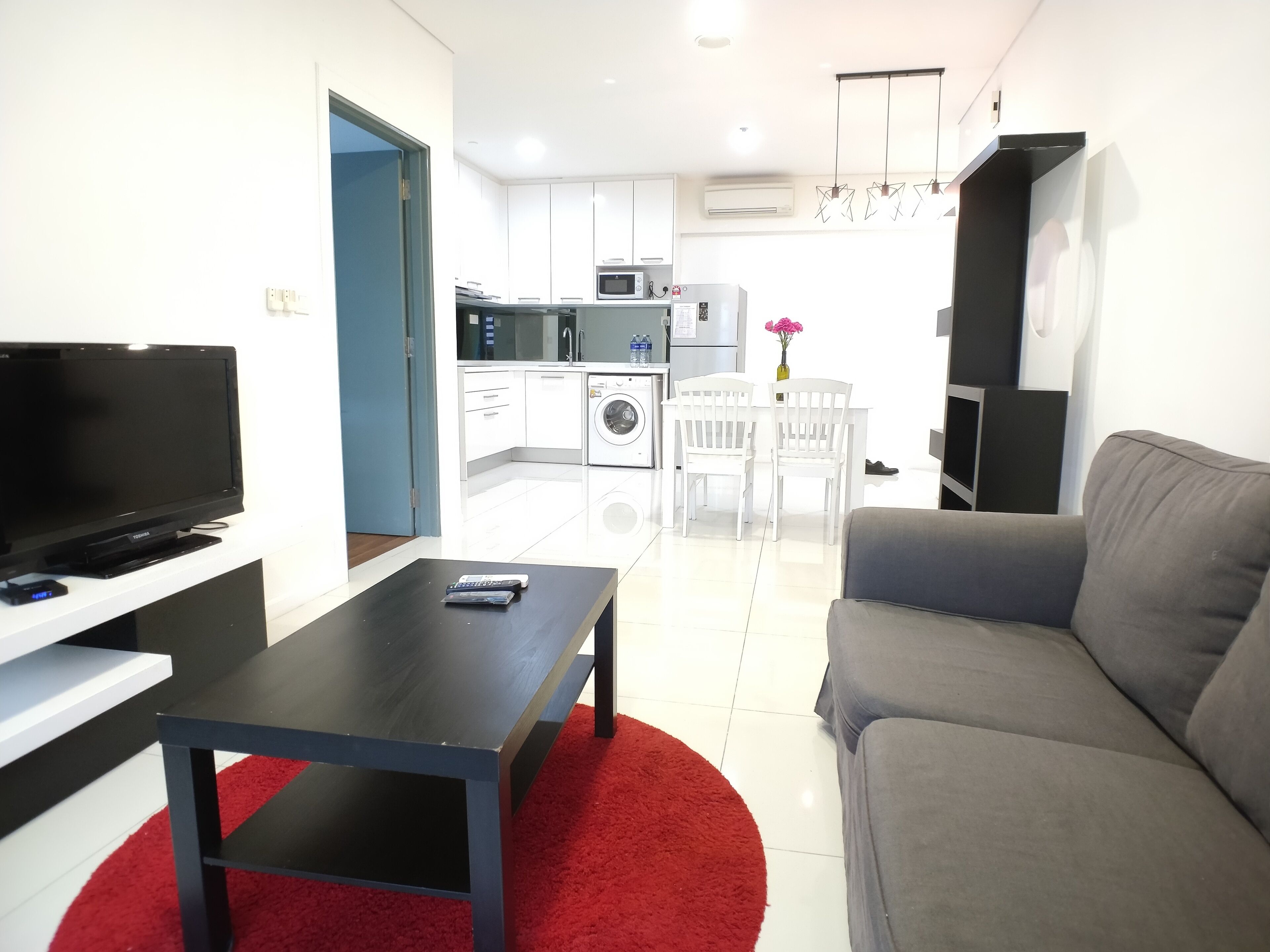 A modern living room with a flat-screen TV, a coffee table, and a gray sofa.