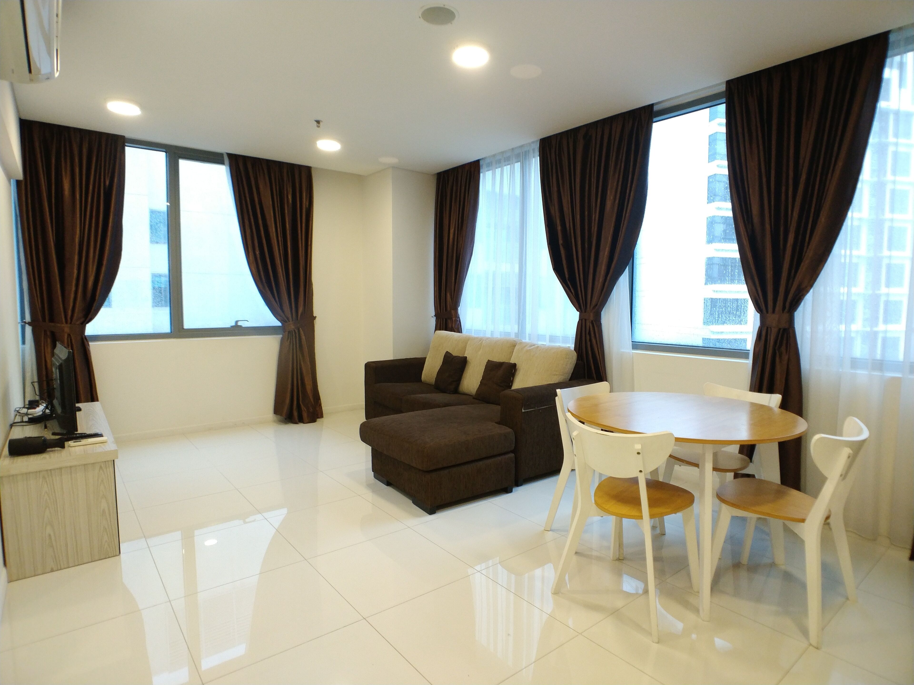 A modern living room with a brown sofa, a round table, and white chairs.