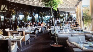 An outdoor dining area with tables and chairs, a tree, and a view of the sea. - Hotel 36 - ORBI Beach Tower Batumi 36th floor (Batumi)