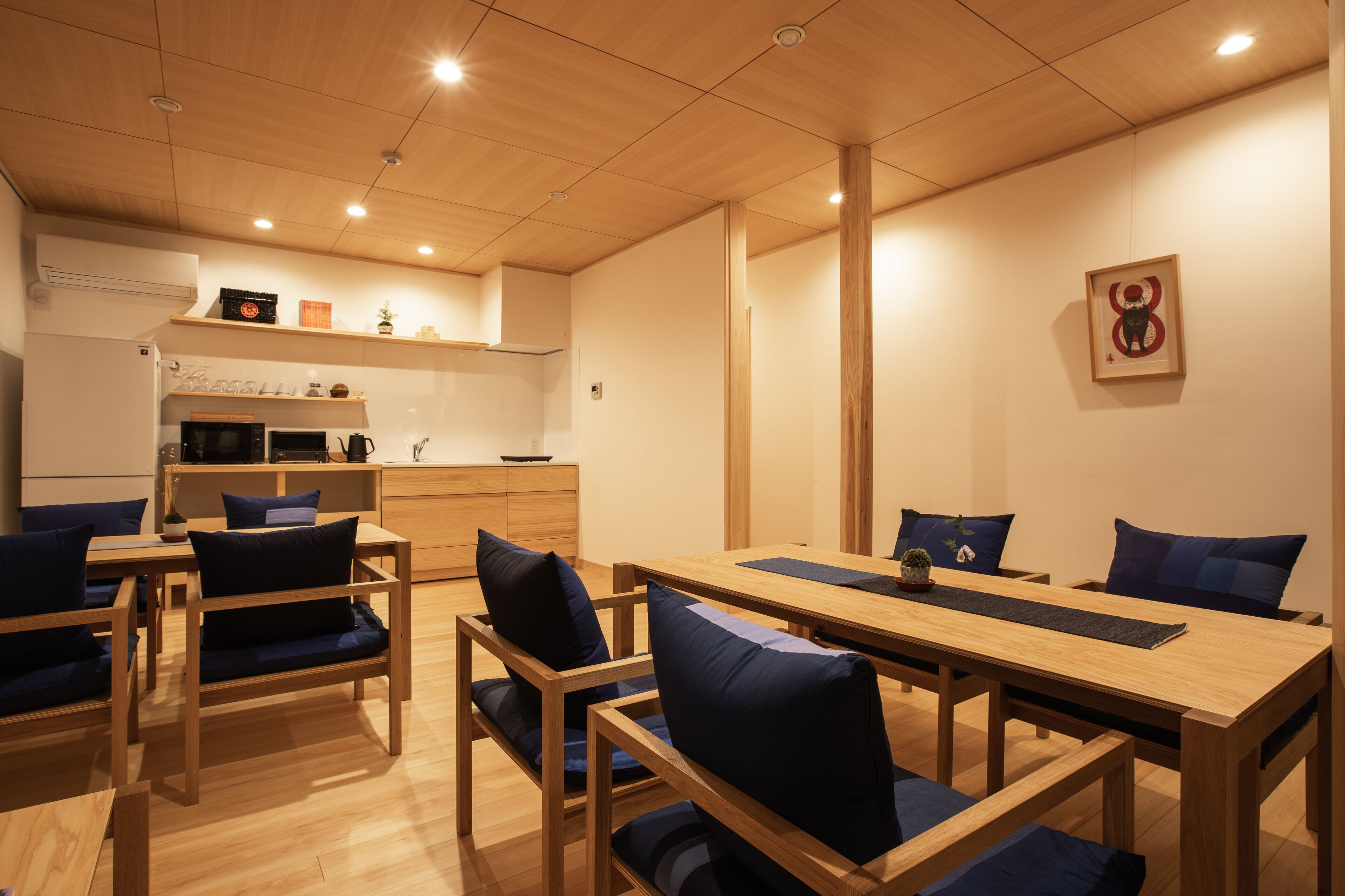A modern dining area with wooden furniture and a kitchen in the background.