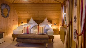 A cozy wooden cabin bedroom with a bed, bedside lamps, and curtains. - Chalet am Birkenhain (Hinterzarten)