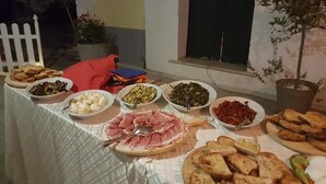A table set with various dishes including bread, meats, and vegetables, outdoors at night. - Lamione da Dorotea (Torchiara)