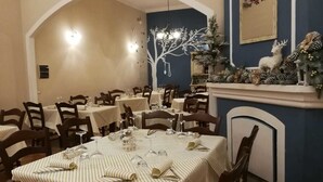 A dining area with round tables, chairs, and a fireplace decorated with pinecones and greenery. - Lamione da Dorotea (Torchiara)
