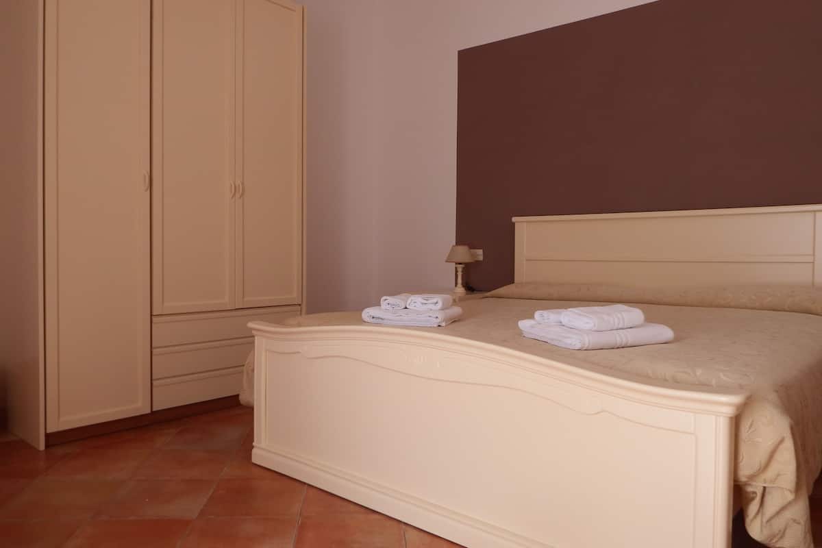 A bedroom with a bed, a wardrobe, and a lamp.