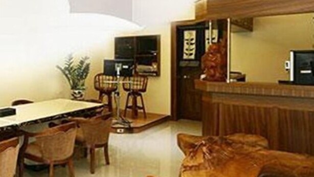 A modern dining area with a wooden table and chairs, a bar area with a wooden counter, and a large wooden sculpture. - Happy Owner Homestay (Ruisui)