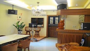 A dining area with a table and chairs, a chandelier, a potted plant, and a kitchen area with cabinets and a microwave. - Happy Owner Homestay (Ruisui)
