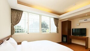 A hotel room with a large bed, a TV, and a window with curtains. - Happy Owner Homestay (Ruisui)