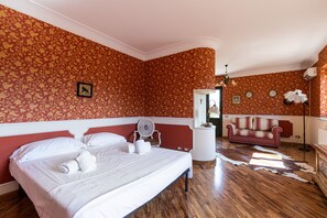 A bedroom with a large bed, a fan, a sofa, and a cowhide rug.