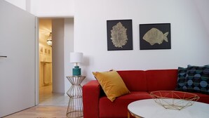 Ett modernt vardagsrum med en röd soffa, ett vitt soffbord och två inramade konstverk med fiskmotiv på väggen.