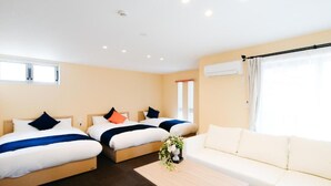 Quarto de hotel com duas camas, um sofá e uma mesinha.
