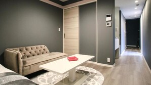 Uma sala de estar moderna com sofá, uma mesinha e uma porta deslizante que dá para outro cômodo.