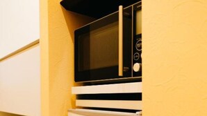 A compact kitchenette with a microwave and refrigerator. - FUKUOKA MOJIKO Stay (Kitakyushu)