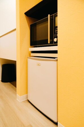 A compact kitchenette with a microwave and refrigerator. - FUKUOKA MOJIKO Stay (Kitakyushu)