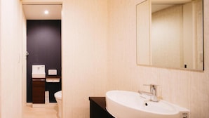 A modern bathroom with a white sink, dark wall, and a mirror. - FUKUOKA MOJIKO Stay (Kitakyushu)