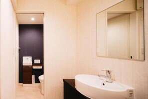 A modern bathroom with a white sink, dark wall, and a mirror. - FUKUOKA MOJIKO Stay (Kitakyushu)