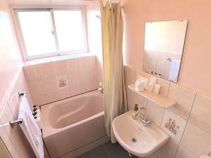 Un baño con bañera, lavabo, espejo y ventana.
