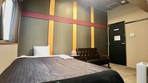 A hotel room with a large bed, a chair, a desk, and a door. - Hotel Time Rich (Okinawa)