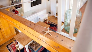 A wooden bench with a starfish decoration, a glass table, and a large glass container in a room with tiled flooring and a patterned rug. - Solemar Sicilia - Casa Olivia (Santa Flavia)