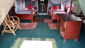 A tent-style room with two wooden beds, each with a canopy, and a wooden table. - Mara Silalei (Narok)