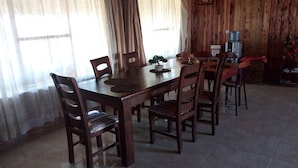 A dining area with a wooden table and chairs, a potted plant, and a water dispenser. - Mara Silalei (Narok)