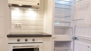 A compact kitchen with a built-in oven, a microwave, and a refrigerator with multiple shelves. - 3-Zimmer Apartment mit 2 Bädern am Marktplatz (Tuebingen)