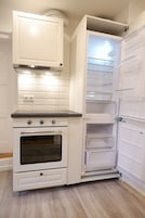 Uma cozinha compacta com forno embutido, micro-ondas e frigorífico com várias prateleiras.
