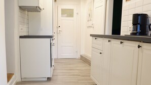 A narrow kitchen with white cabinets, a black countertop, and a coffee machine. - 3-Zimmer Apartment mit 2 Bädern am Marktplatz (Tuebingen)