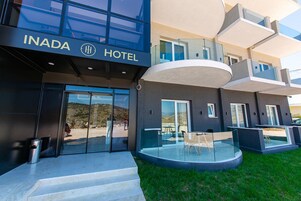 Un hotel moderno con fachada de vidrio, zona de estar al aire libre y vistas despejadas del paisaje circundante.