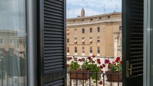 A balcony with potted plants and a view of a building with multiple windows and balconies. - Italianway - Sant'Oronzo Apartment (Lecce)