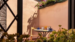 Une terrasse ensoleillée avec une table dressée pour deux personnes, comprenant une chaise et une petite table.