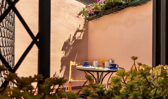 A sunlit patio with a table set for two, featuring a chair and a small table.