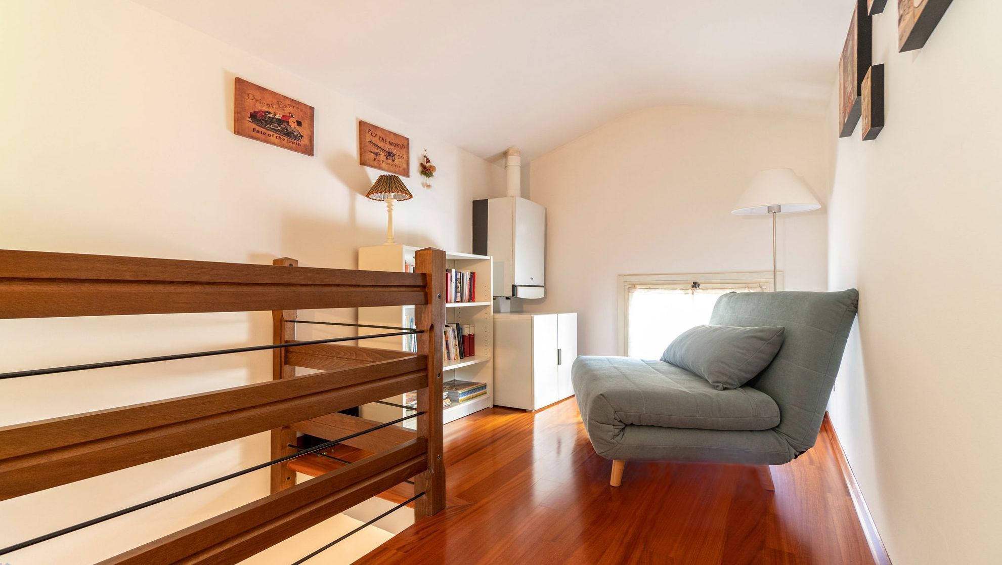 Una sala de estar moderna con un banco de madera, un sofá gris, un armario blanco y una estantería.