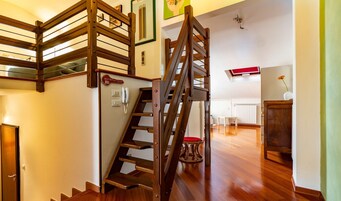 A wooden staircase with a red cushioned seat at the bottom, a wall-mounted phone, and a sign reading "Bistrottes Bar."